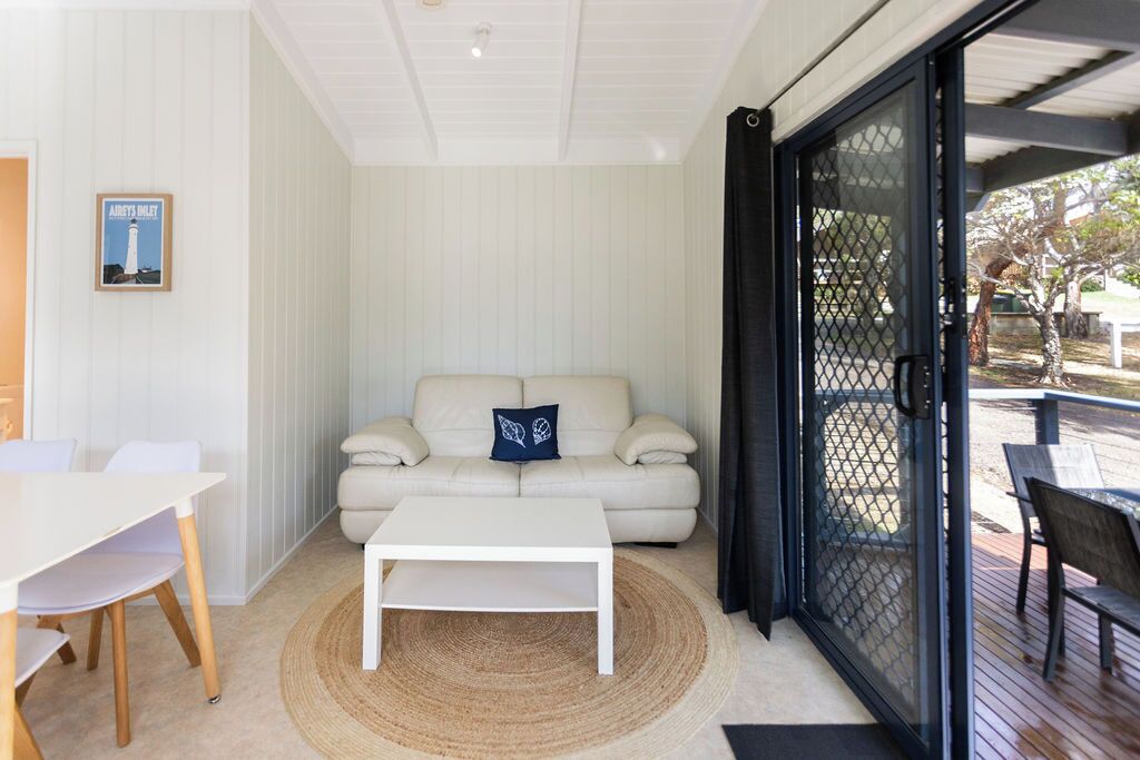 Un salon moderne avec un canapé blanc, une table basse blanche et un coin repas comprenant une table et des chaises blanches.