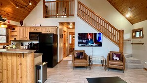 A spacious living area with a kitchen, a dining area, and a TV mounted on the wall. - Lovekin Cabin - Prescott Cabin Rentals (Prescott)