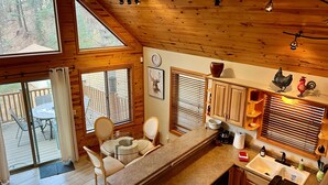 A kitchen with a central island, wooden cabinets, a sink, and a dining area with chairs and a table. - Lovekin Cabin - Prescott Cabin Rentals (Prescott)