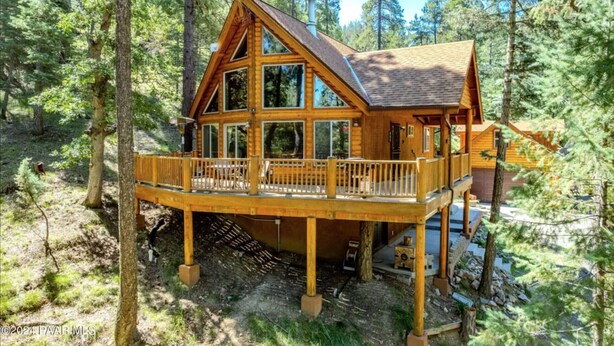 A wooden cabin with a deck, surrounded by trees. - Lovekin Cabin - Prescott Cabin Rentals (Prescott)