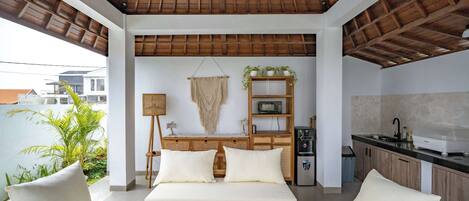 A modern living area with a sofa set, a wooden coffee table, and a kitchen area with a sink and cabinets.
