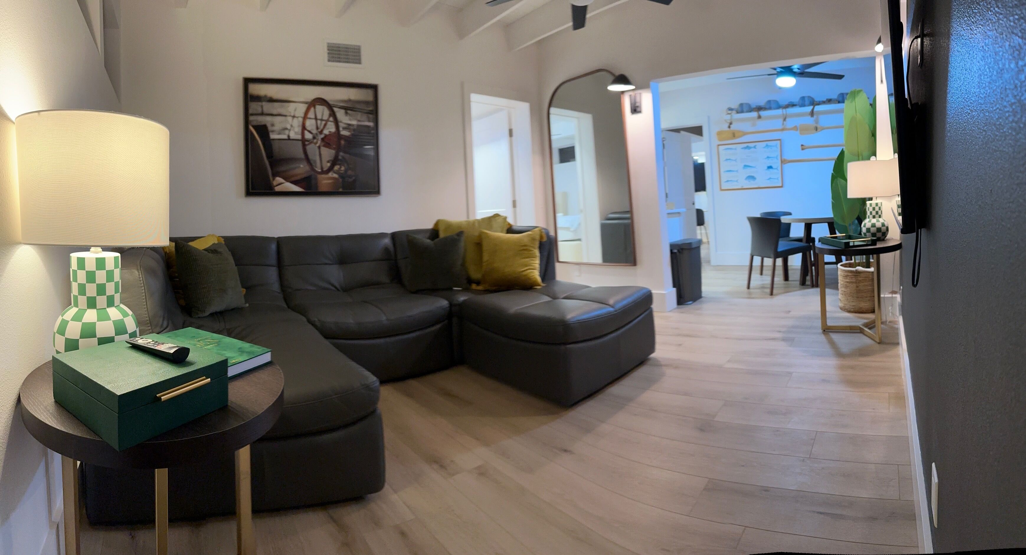 A modern living room with a sectional sofa, a small side table with a lamp, and a remote control on the sofa.
