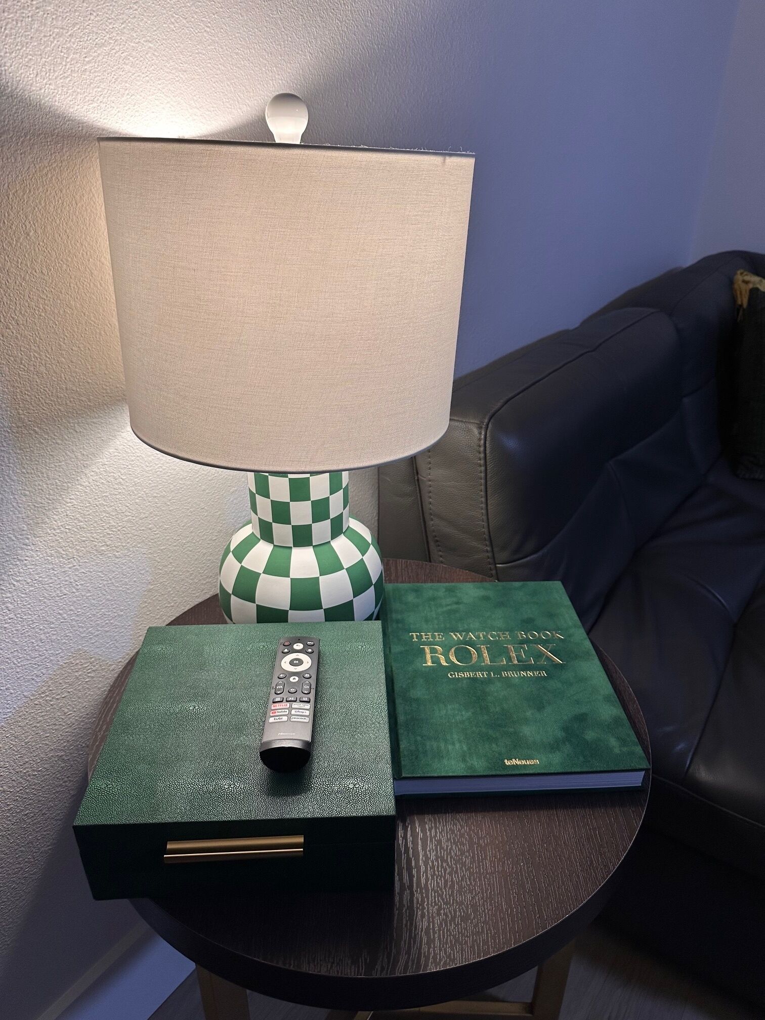 A lamp, a remote control, and a book on a small table.