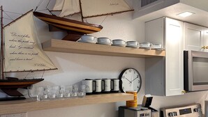 A kitchen with a wooden ship model, a clock, and a coffee maker. - Siesta Key Cottage – Best Value! Just Cross the Street to the Gulf! (Siesta Key)