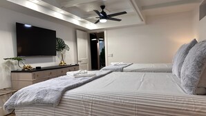 A modern bedroom with a large bed, a ceiling fan, a flat-screen TV, and a bedside table with a plant. - Siesta Key Cottage – Best Value! Just Cross the Street to the Gulf! (Siesta Key)