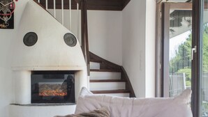 A modern living room with a fireplace, a staircase, and a view through a glass door. - Waldblick by Interhome (Winterberg)