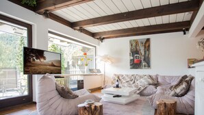 A cozy living room with a large window, a flat-screen TV, a sofa set, a coffee table, and a painting on the wall. - Waldblick by Interhome (Winterberg)