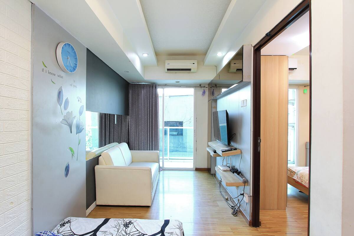 A modern living room with a sofa, TV, and a dining area with a table and chairs.