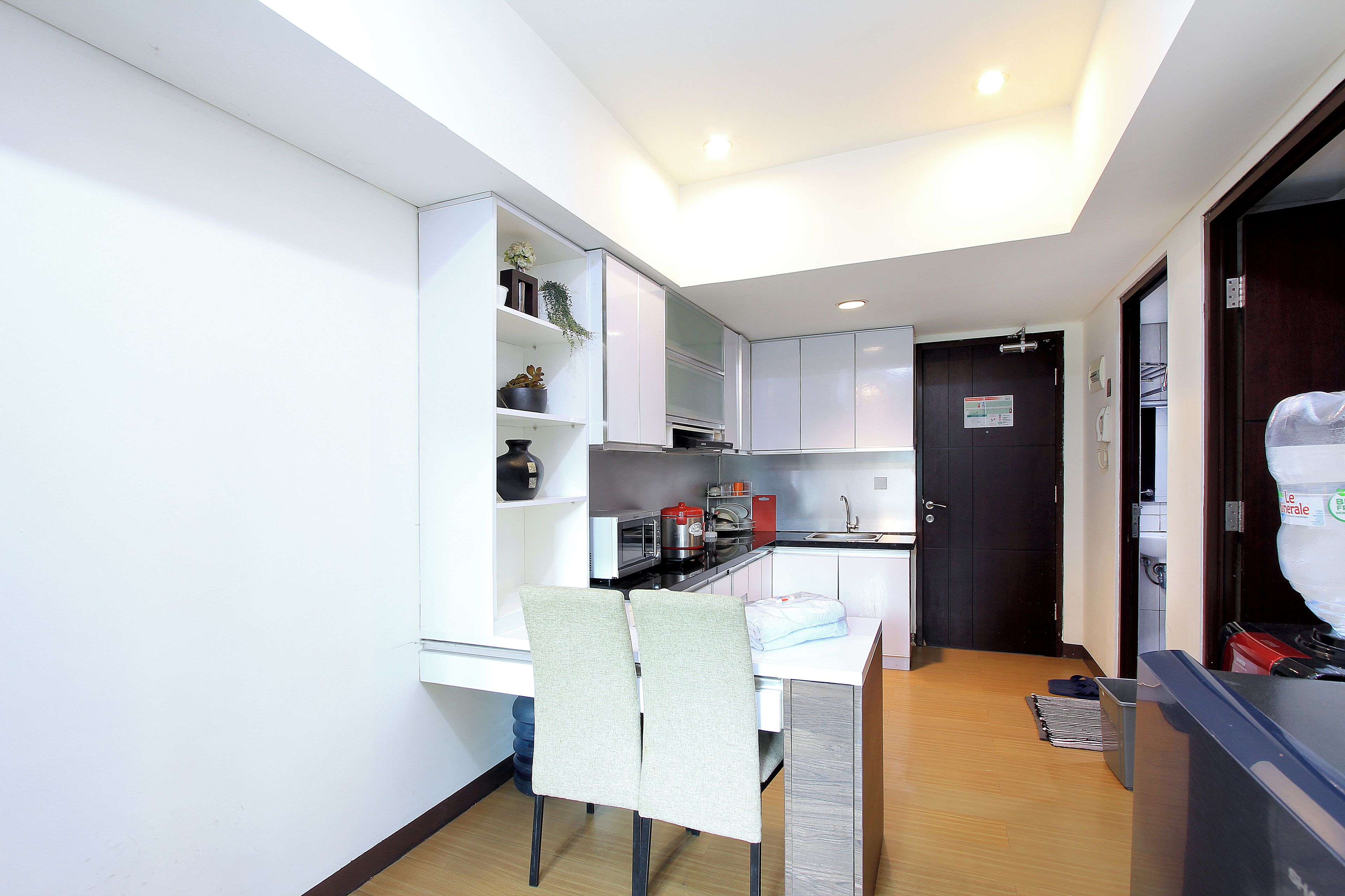 A compact kitchen with white cabinets, a dining table with two chairs, and a small countertop.