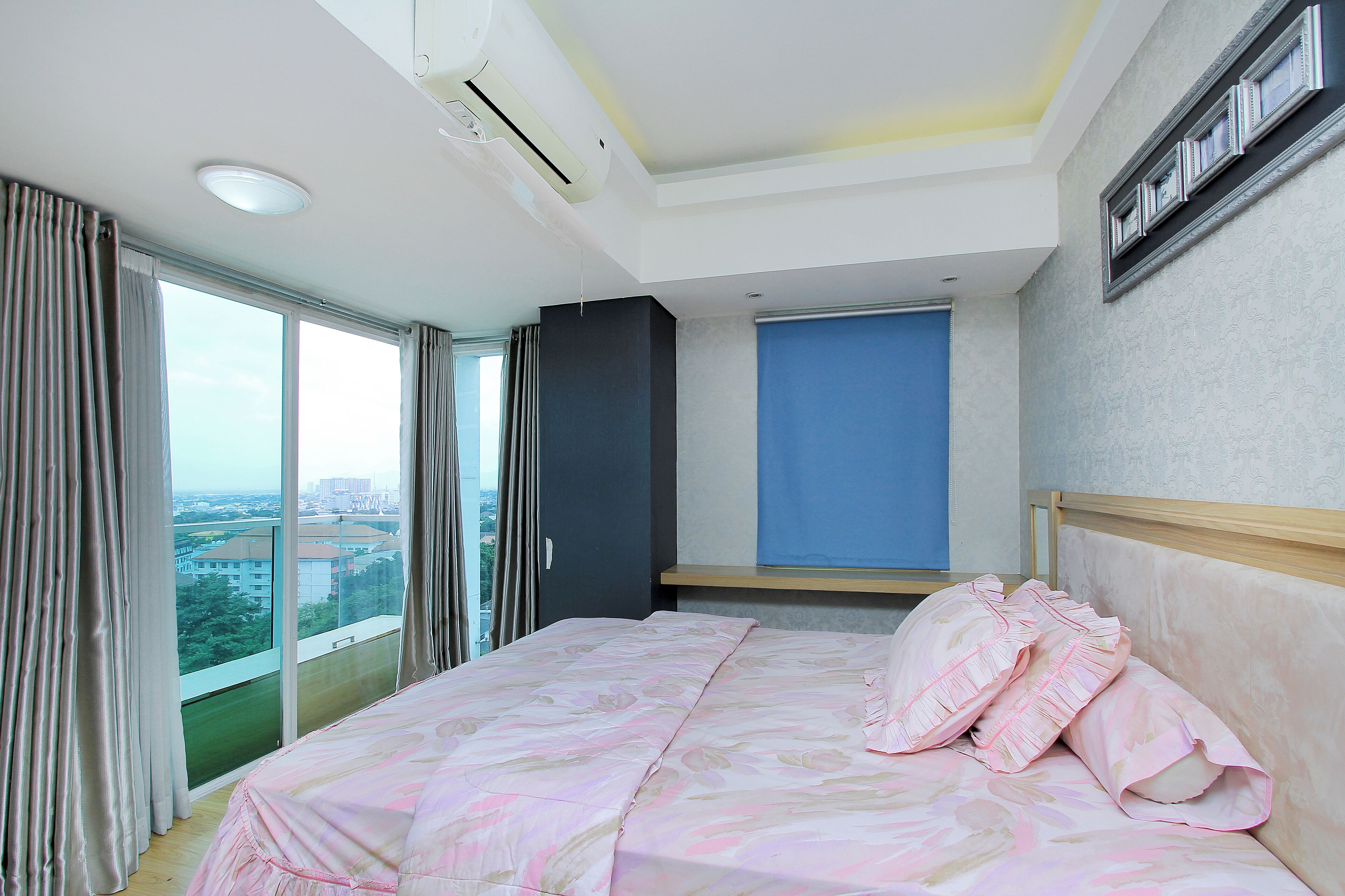 Un dormitorio con una cama grande, vistas a la ciudad y una ventana con cortinas.