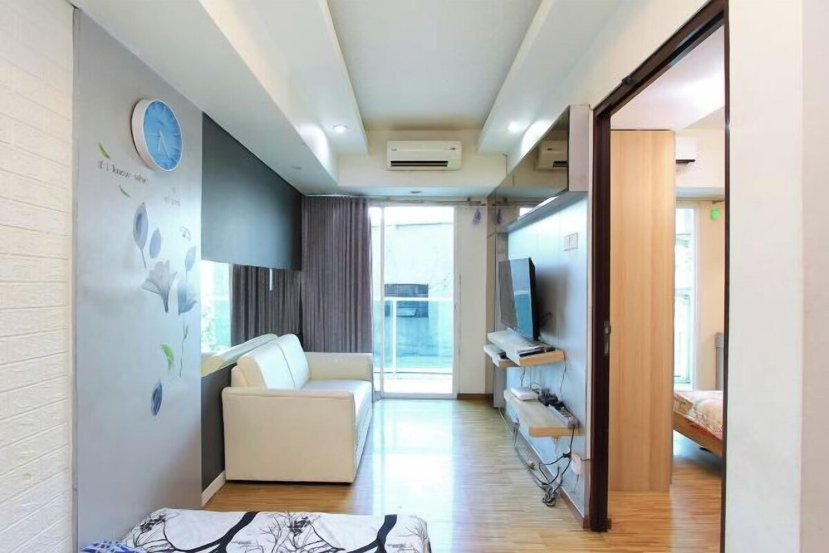 Una habitación de hotel moderna con un sofá, un televisor y un mueble de madera.