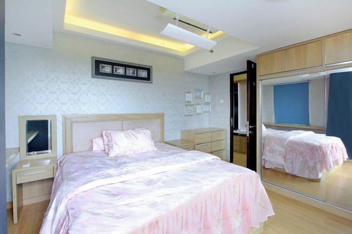 Un dormitorio con cama, mesitas de noche, un espejo y un armario.
