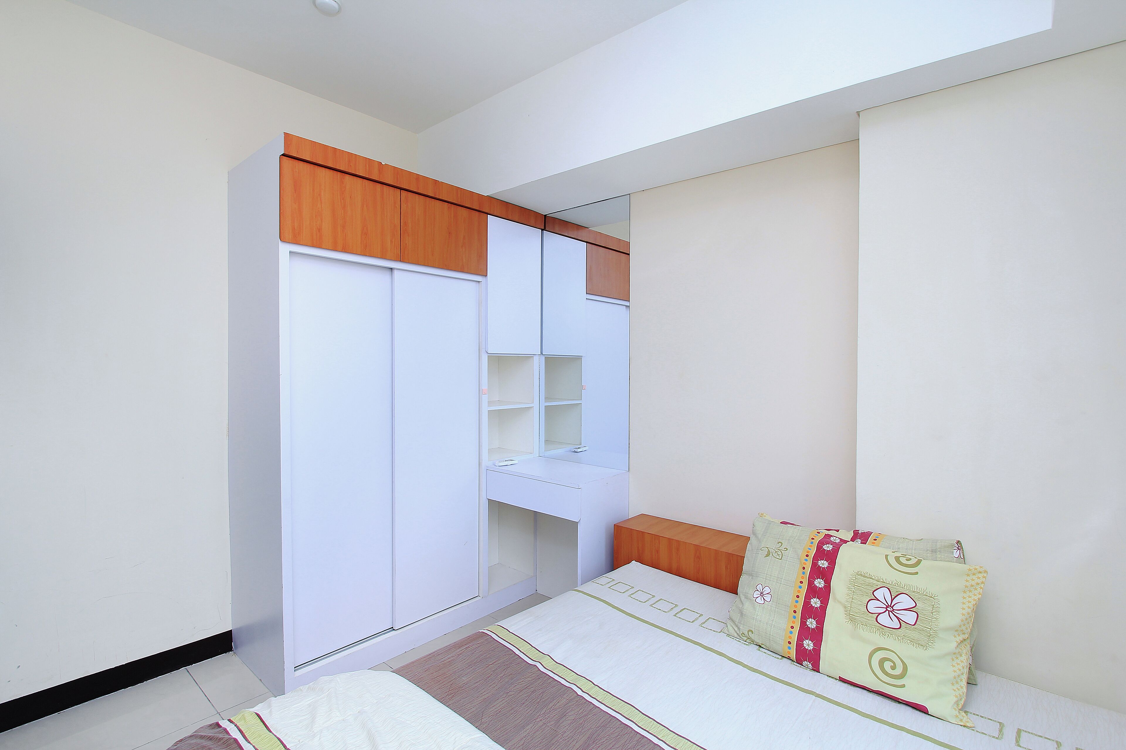 A bedroom with a bed, a wardrobe, a desk, and a mirror.