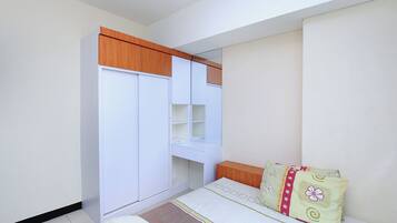 A bedroom with a bed, a wardrobe, a desk, and a mirror.