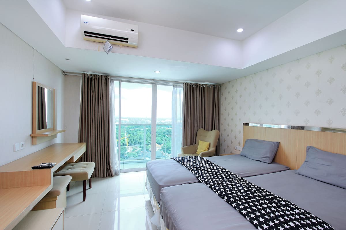 A hotel room with a bed, a desk, a chair, and a large window with curtains.