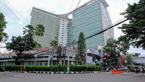A modern building with multiple floors, surrounded by greenery and power lines. - La Grande by Djitu Hospitality (Bandung)