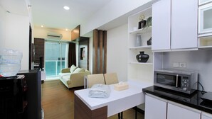 A compact hotel room with a kitchenette, a dining area, and a living space. - La Grande by Djitu Hospitality (Bandung)