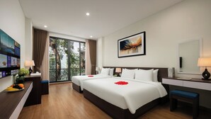 A hotel room with two beds, a desk, a chair, a TV, and a balcony with a view of trees. - Queen Cafe Hotel (Hanoi)