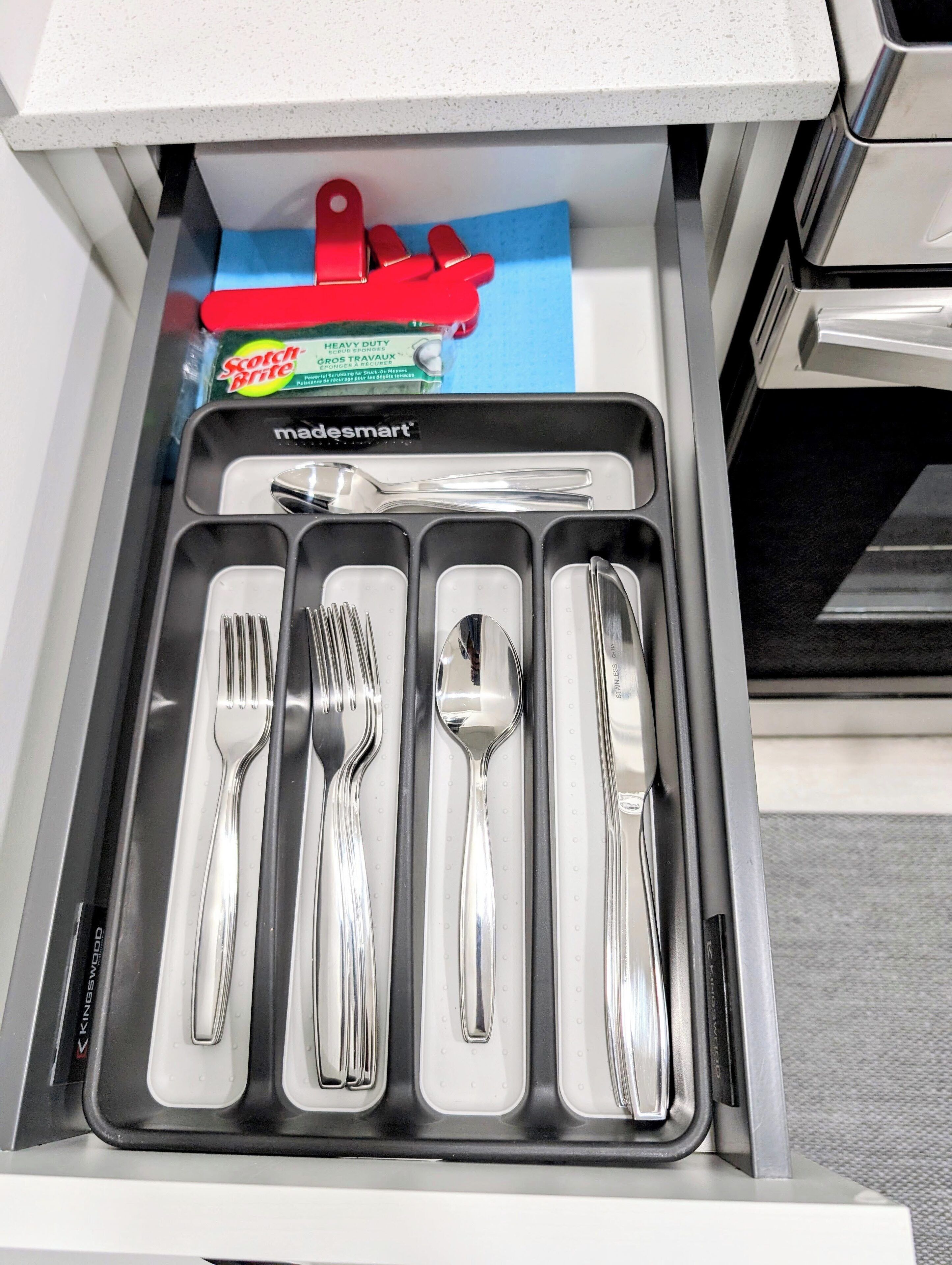 A drawer with a set of silverware neatly arranged in compartments.