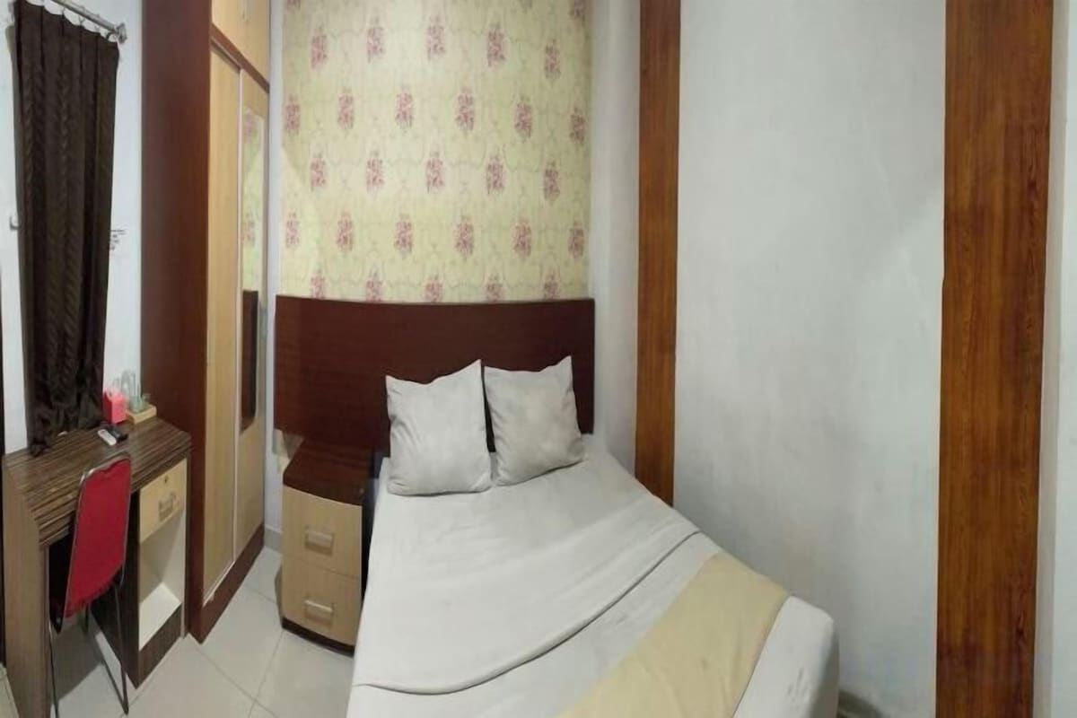 A bedroom with a bed, a desk, and a chair.