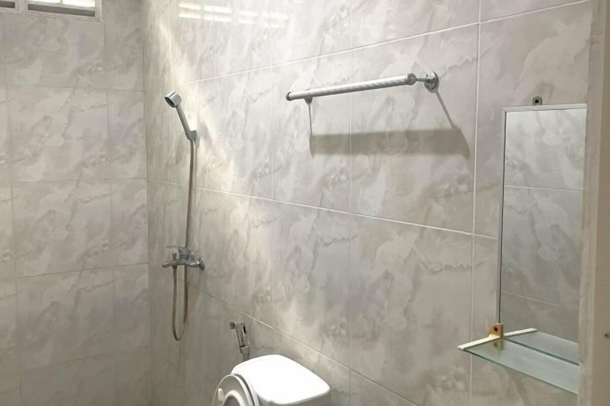 A bathroom with a shower, toilet, and a glass shelf.