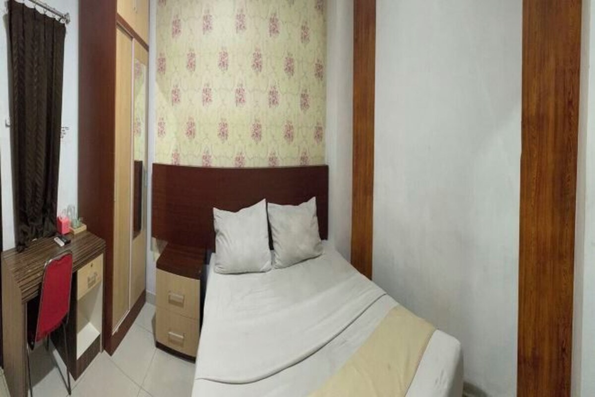 A small, neatly arranged bedroom with a bed, a desk, and a chair.