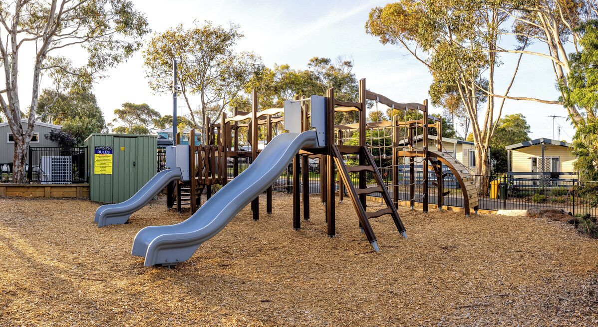A playground with two slides and a climbing structure.