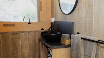A bathroom with a wooden vanity, a black sink, a mirror, and a towel rack.