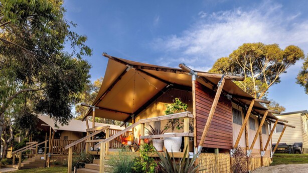 Une cabane en bois dotée d’un porche couvert, d’un espace salon extérieur et d’un jardin.