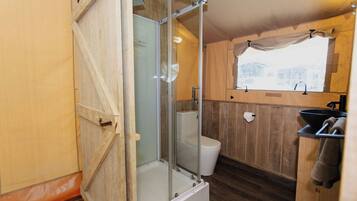 Un baño pequeño con cabina de ducha, inodoro y lavamanos.
