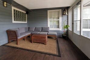 A room with a sectional sofa, a wooden bench, a potted plant, and a window with blinds. - Pool, Spa, Bar + Game Room - Huntsville Lake House (Huntsville)