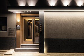 A hotel entrance with a modern design, featuring a well-lit pathway leading to the door, a sign indicating room number 23, and a textured wall facade. - HOTEL SEPT. JONGNO (Seoul)