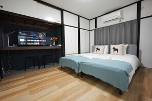 A modern bedroom with a bed, a desk with a computer, and an air conditioner. - Otabiya Nishikujo (Osaka)