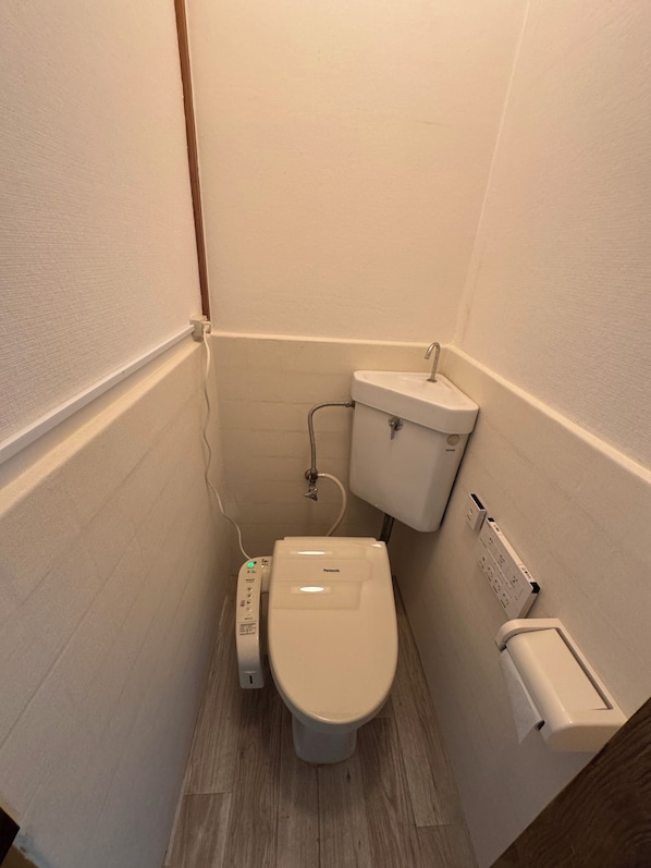A small, compact bathroom with a toilet, a bidet, and a hand dryer. - Otabiya Nishikujo (Osaka)