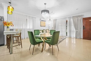 A dining area with a round table, green upholstered chairs, and a chandelier. - Cozy 2-bedroom Apartment in Santo Domingo's Heart (Santo Domingo)