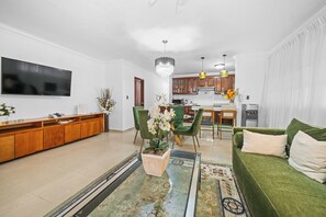 A modern living room with a green sofa, a coffee table, and a TV mounted on the wall. - Cozy 2-bedroom Apartment in Santo Domingo's Heart (Santo Domingo)