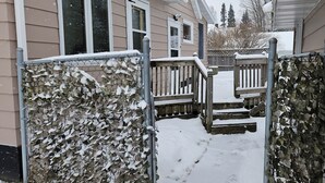 A snow-covered pathway leading to a wooden deck with steps. - Snowmobile, UTV trails, Fishing in a charming 3-bedroom house in Republic (Republic)
