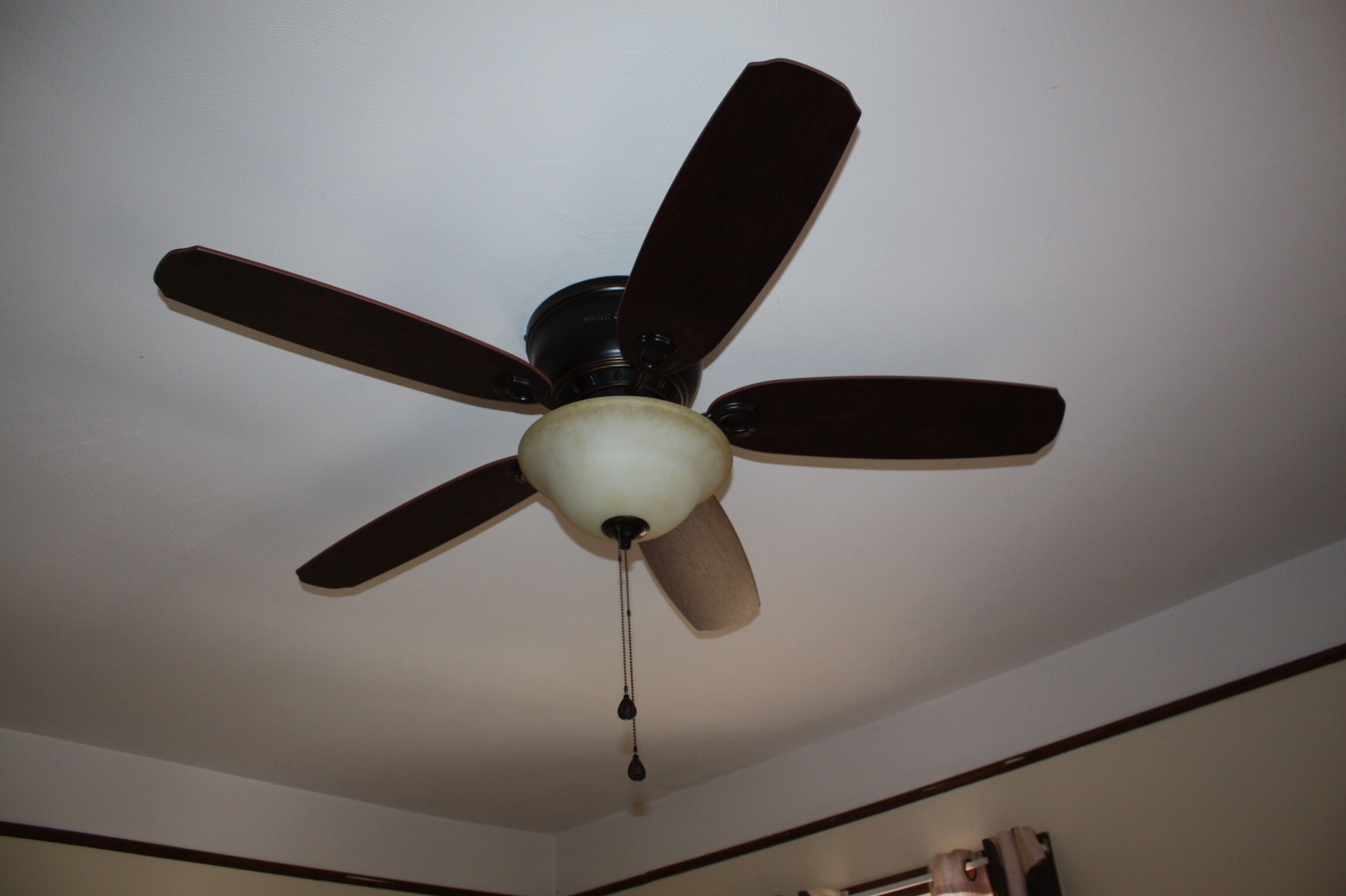 A ceiling fan with five blades and a central light fixture.
