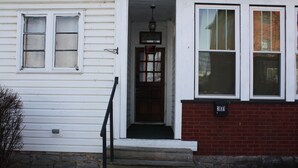 A white house with a brick foundation, a front door, and a number '301' sign. - All one floor Charming large2 bedroom, LR, sunrm, kitchen, 1 Full & 1 half bath (Roaring Spring)