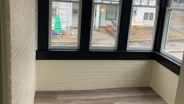 A room with a bay window overlooking a yard with a Christmas tree. - All one floor Charming large2 bedroom, LR, sunrm, kitchen, 1 Full & 1 half bath (Roaring Spring)