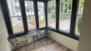 Una habitación con techo de madera, ventanas amplias, una mesa con sillas y una pared de ladrillo.
