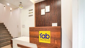 A reception desk with a wooden finish and a yellow logo for Fab Hotels. - Fabhotel The Pleasure Stay (Varanasi)
