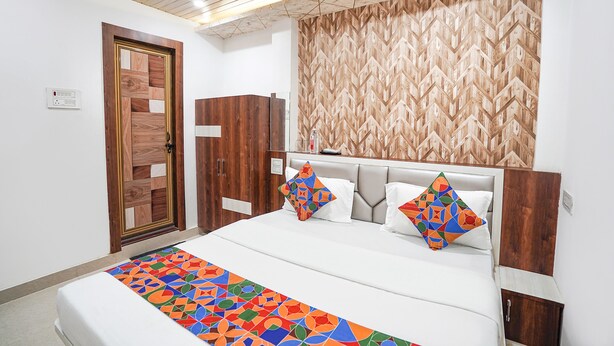 A bedroom with a bed, wooden wardrobe, and a patterned wall. - Fabhotel The Pleasure Stay (Varanasi)