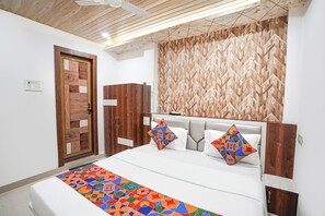 A bedroom with a bed, wooden wardrobe, and a patterned wall. - Fabhotel The Pleasure Stay (Varanasi)