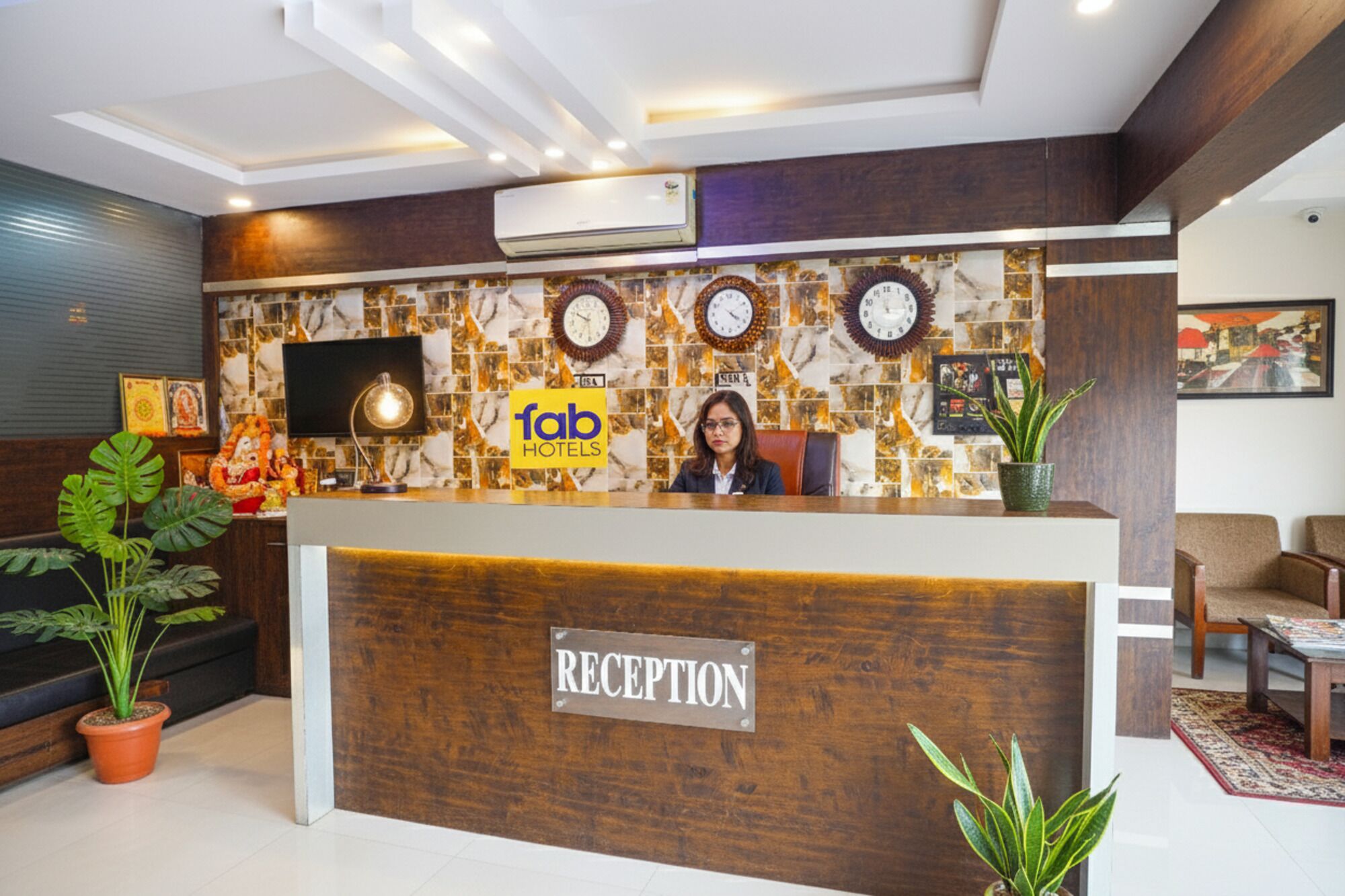 A reception desk with a 'fab hotels' sign, a clock, and a wall with a mosaic pattern.