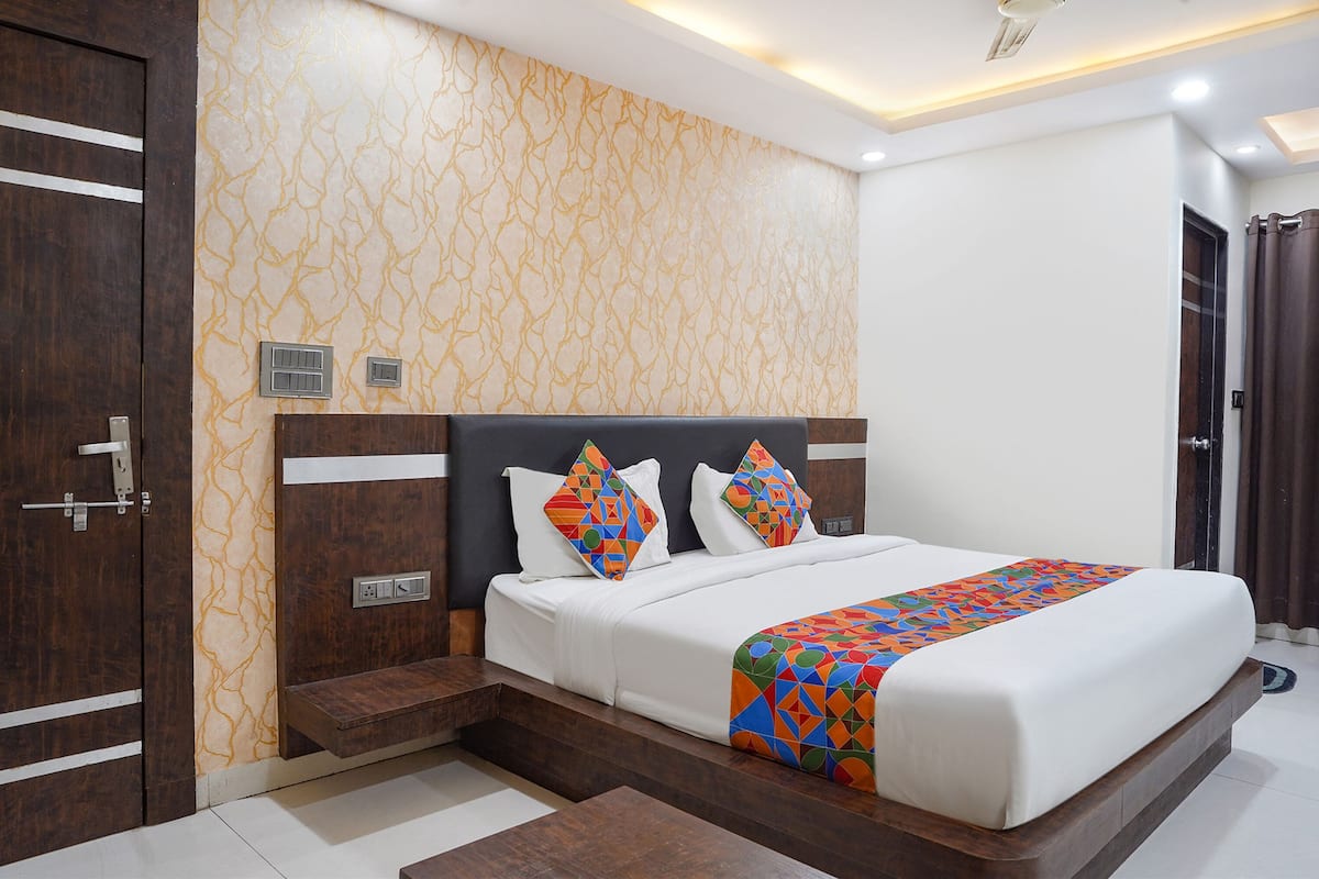 Une chambre d’hôtel moderne avec un grand lit, une tête de lit en bois et un mur orné d’un motif.