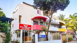 A two-story building with a red and white facade, a balcony, and a sign for Falcon Inn A/C Rooms. - FabHotel New Falcon Inn (Pune)