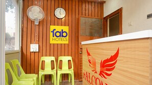 A reception area with a wooden wall, a clock, a fan, and a sign for 'Fab Hotels'. - FabHotel New Falcon Inn (Pune)