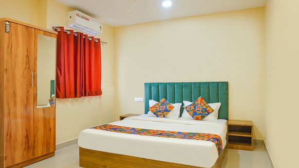 A bedroom with a bed, a wardrobe, a ceiling fan, and an air conditioning unit. - FabHotel New Falcon Inn (Pune)