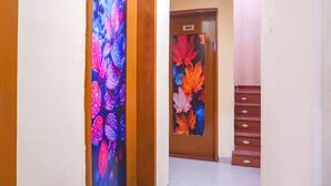A hallway with a wooden door marked '203' and a glass door with colorful leaf patterns. - FabHotel New Falcon Inn (Pune)